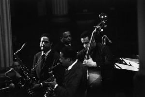 FRANCE. Paris. CHARLIE MINGUS SEXTET. 1964. In the foreground: American alto saxophonist Eric DOLPHY (center). In the background, from left to right: American jazz musicians Clifford JORDAN (tenor saxophone), Charles MINGUS (doublebass) and Jaki BYARD (saxophones, piano, trumpet).  Contact email: New York : photography@magnumphotos.com Paris : magnum@magnumphotos.fr London : magnum@magnumphotos.co.uk Tokyo : tokyo@magnumphotos.co.jp Contact phones: New York : +1 212 929 6000 Paris: + 33 1 53 42 50 00 London: + 44 20 7490 1771 Tokyo: + 81 3 3219 0771 Image URL: http://www.magnumphotos.com/Archive/C.aspx?VP3=ViewBox_VPage&IID=2TYRYDJ45CZ&CT=Image&IT=ZoomImage01_VForm